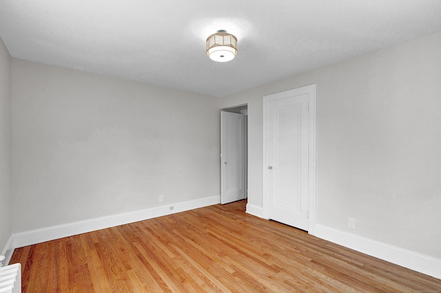 empty room with a textured ceiling and light wood-type flooring