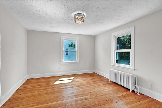 unfurnished room with radiator heating unit, a textured ceiling, and light hardwood / wood-style floors