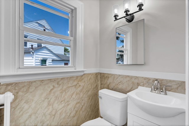 bathroom featuring vanity, toilet, and tile walls