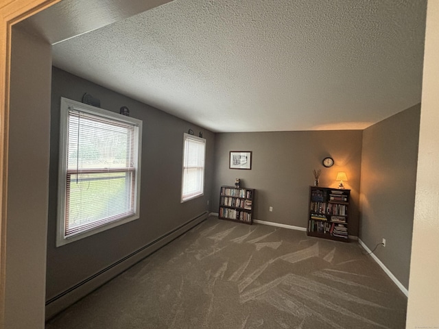 carpeted empty room featuring baseboard heating and a textured ceiling