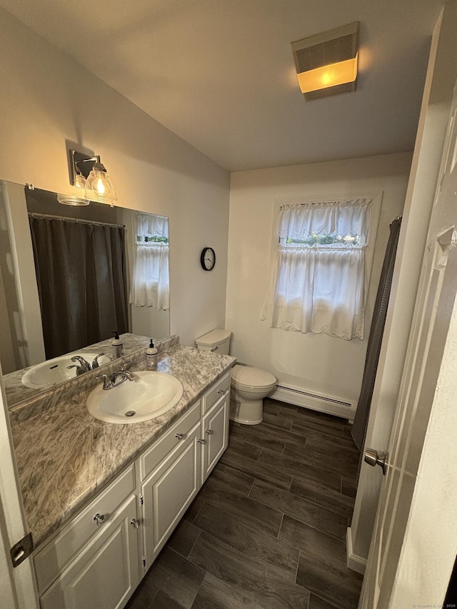 bathroom with toilet, hardwood / wood-style floors, vanity, and a baseboard heating unit