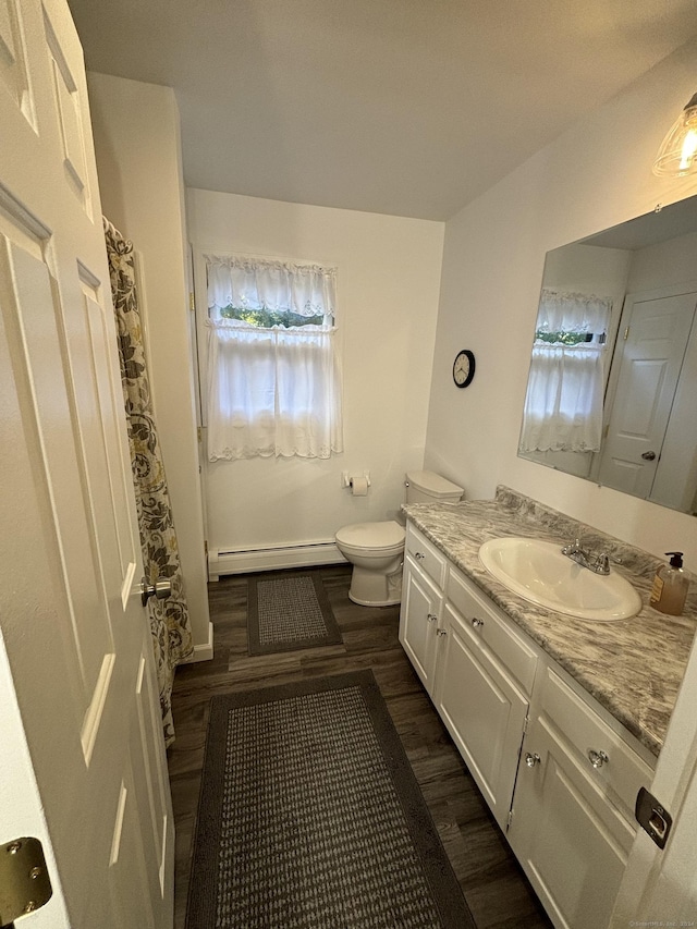 bathroom with hardwood / wood-style floors, vanity, toilet, and a baseboard heating unit