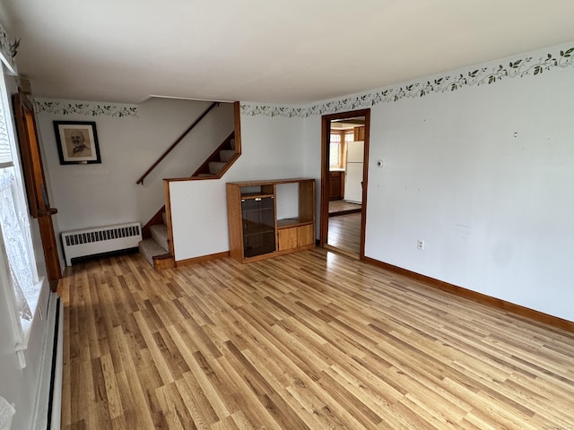 unfurnished living room featuring radiator heating unit, light wood-type flooring, and a baseboard radiator