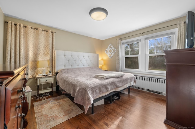 bedroom with dark hardwood / wood-style flooring and radiator heating unit