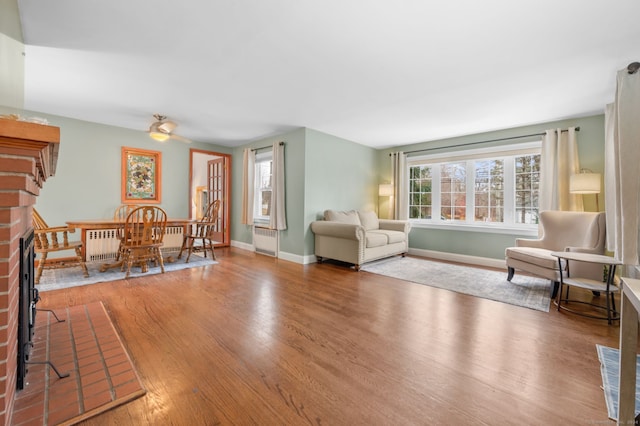 living room with hardwood / wood-style floors, radiator heating unit, and a brick fireplace