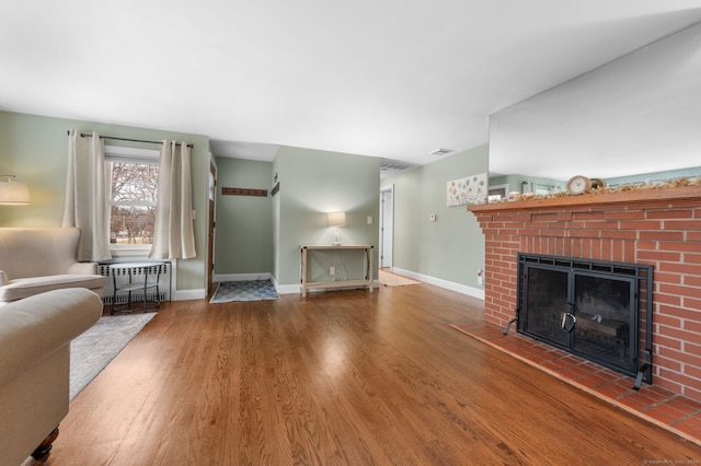 unfurnished living room featuring hardwood / wood-style floors, radiator heating unit, and a brick fireplace