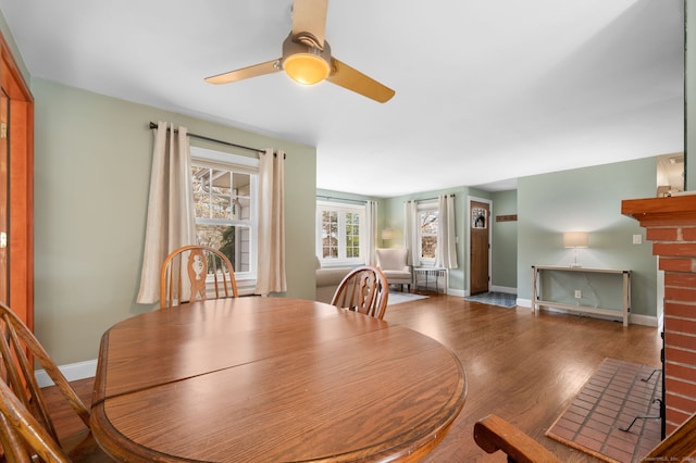 dining room featuring dark hardwood / wood-style flooring, ceiling fan, and a fireplace