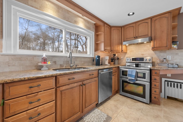 kitchen with radiator heating unit, stainless steel appliances, light stone counters, and sink