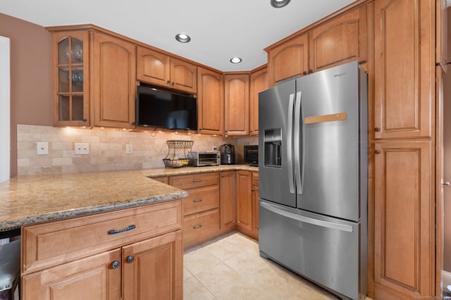 kitchen featuring tasteful backsplash, light stone countertops, light tile patterned flooring, and stainless steel appliances