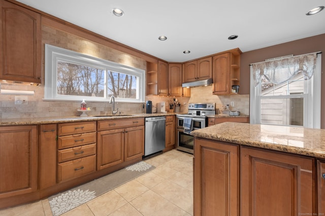 kitchen with sink, light stone counters, backsplash, light tile patterned floors, and appliances with stainless steel finishes