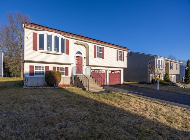 raised ranch featuring an attached garage, driveway, and a front yard