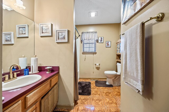 bathroom featuring a textured ceiling, vanity, toilet, and tile patterned floors