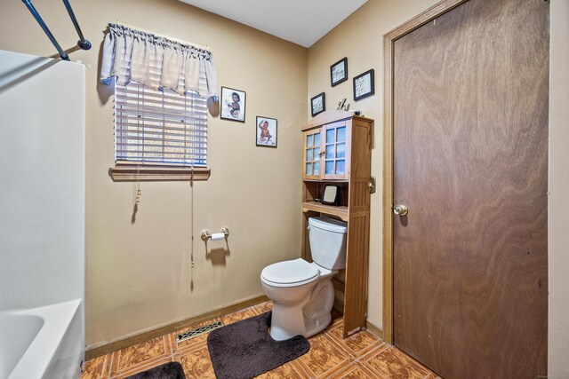 bathroom featuring tile patterned floors, a washtub, and toilet