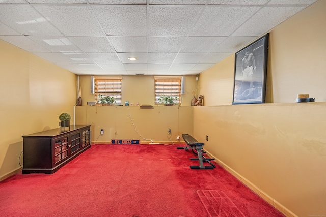 exercise area featuring baseboards, a paneled ceiling, and carpet