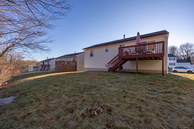 rear view of property featuring stairway, a lawn, fence, and a wooden deck