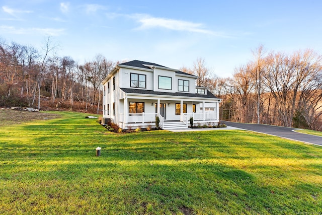 view of front facade featuring a porch, a front yard, and aphalt driveway