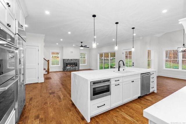 kitchen with a kitchen island with sink, sink, pendant lighting, dishwasher, and white cabinetry