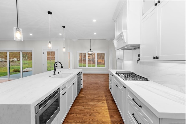 kitchen featuring stainless steel appliances, sink, pendant lighting, white cabinetry, and a large island