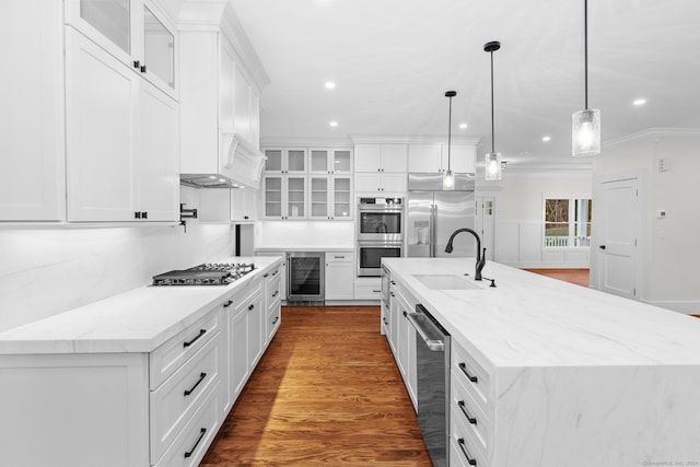 kitchen with a large island with sink, white cabinetry, beverage cooler, and sink