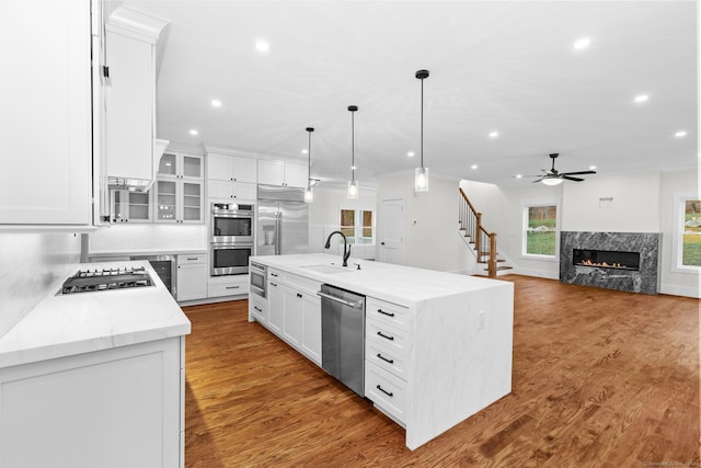 kitchen featuring built in appliances, light stone counters, a spacious island, and white cabinets