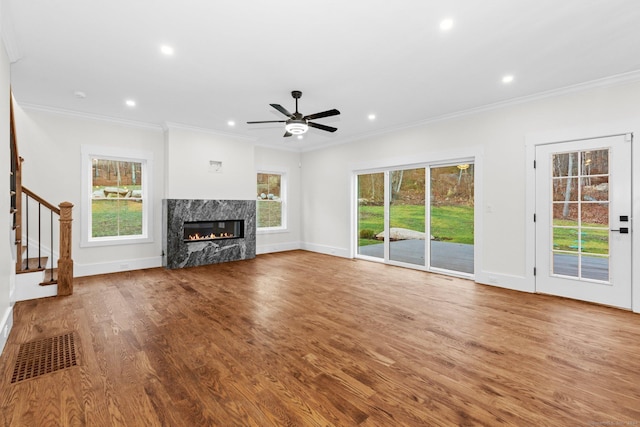 unfurnished living room with wood-type flooring, a premium fireplace, and ornamental molding