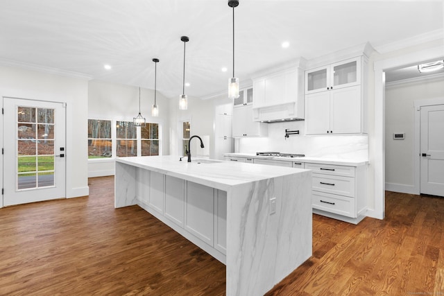 kitchen featuring dark wood-style flooring, a spacious island, ornamental molding, white cabinets, and a sink