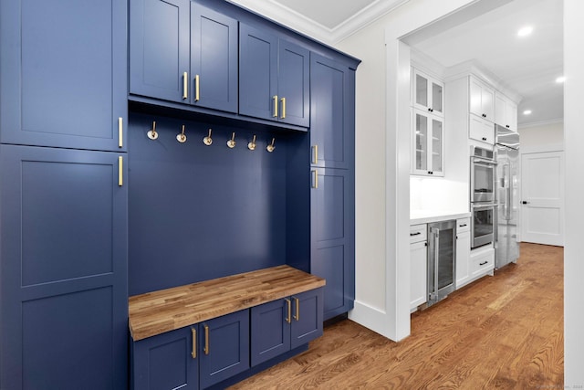 mudroom with wine cooler, crown molding, and dark hardwood / wood-style floors