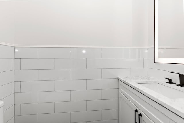 bathroom with vanity, toilet, and tile walls