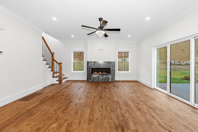 unfurnished living room with hardwood / wood-style flooring, ceiling fan, ornamental molding, and a high end fireplace