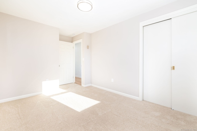 unfurnished bedroom with light colored carpet and a closet