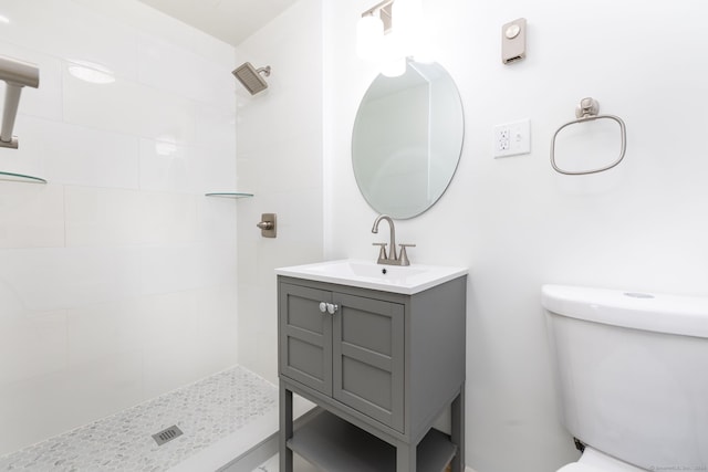 bathroom featuring vanity, toilet, and tiled shower