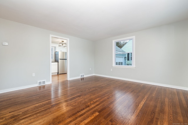 empty room featuring dark hardwood / wood-style flooring and an inviting chandelier