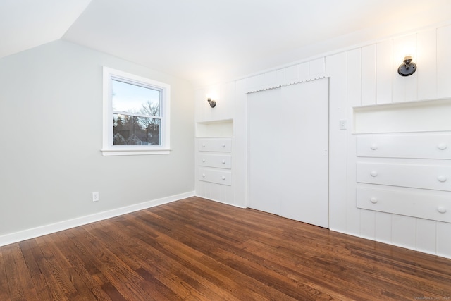 unfurnished bedroom with lofted ceiling and dark wood-type flooring