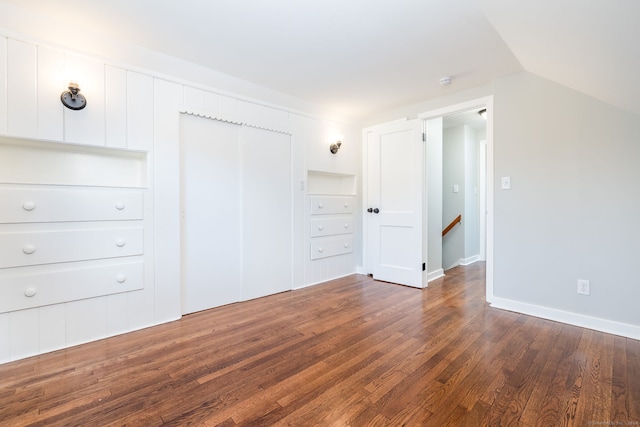 unfurnished bedroom with dark hardwood / wood-style floors, lofted ceiling, and a closet