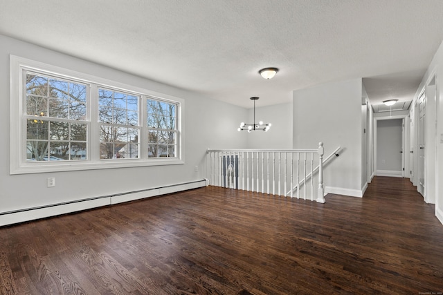 unfurnished room featuring a textured ceiling, dark hardwood / wood-style floors, baseboard heating, and a notable chandelier