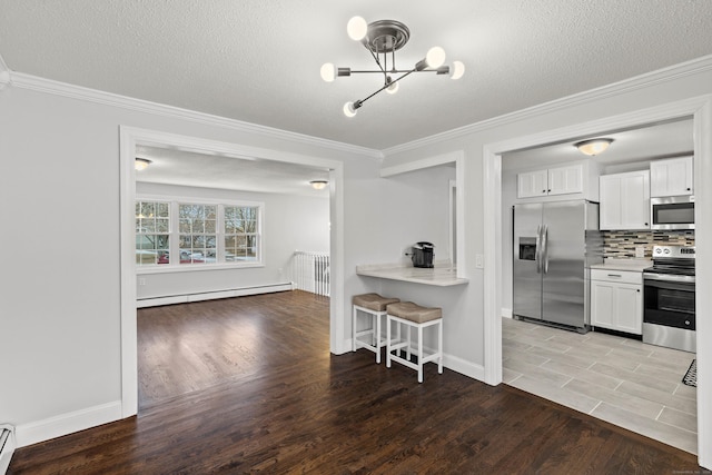 kitchen with white cabinetry, light hardwood / wood-style floors, a baseboard radiator, and appliances with stainless steel finishes