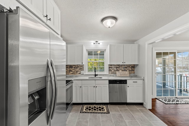 kitchen with white cabinetry, sink, light hardwood / wood-style flooring, backsplash, and appliances with stainless steel finishes