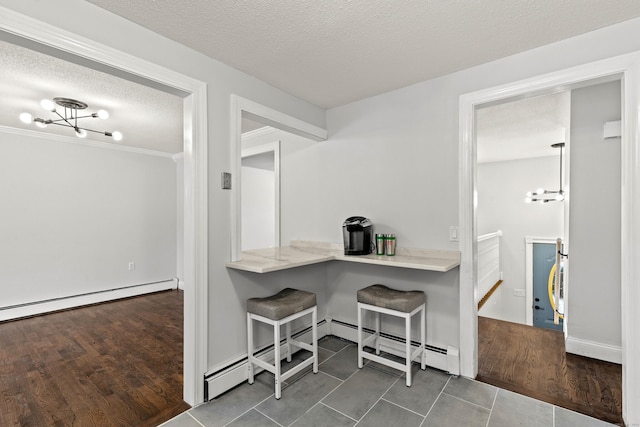 kitchen featuring a kitchen breakfast bar, baseboard heating, dark hardwood / wood-style flooring, a notable chandelier, and a textured ceiling