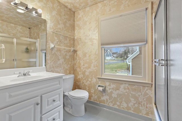 bathroom featuring tile patterned floors, vanity, an enclosed shower, and toilet