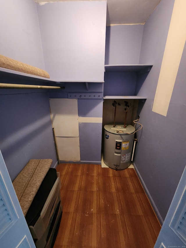 walk in closet featuring water heater and dark hardwood / wood-style flooring