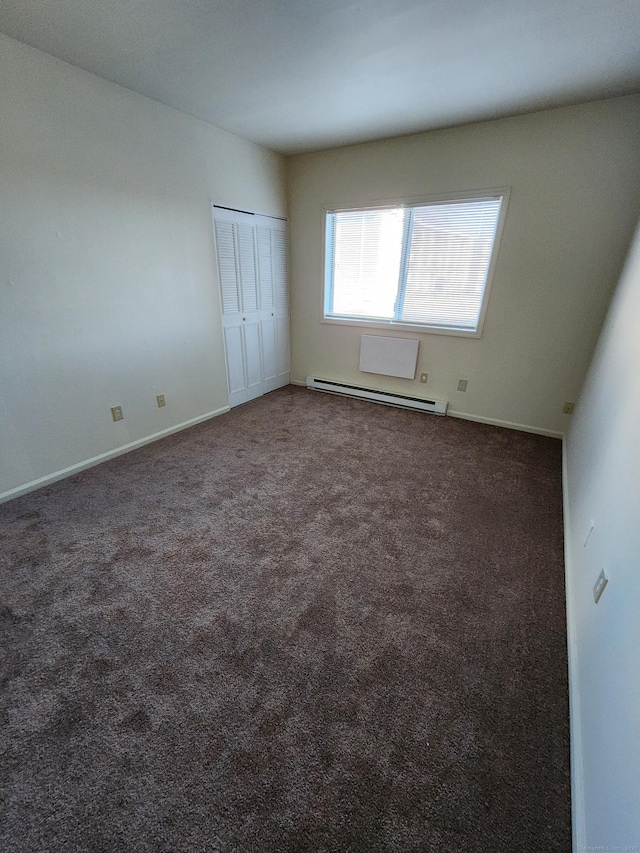 unfurnished room featuring a baseboard heating unit and dark colored carpet