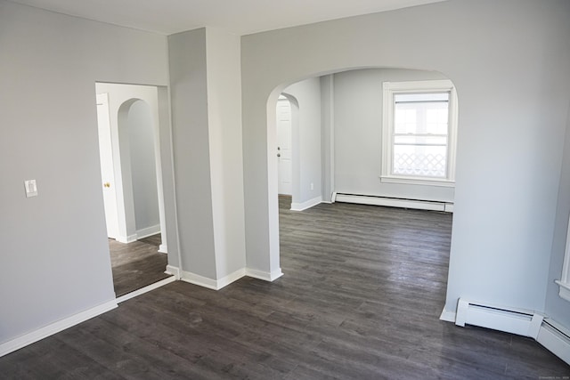 spare room featuring dark wood-type flooring and a baseboard radiator