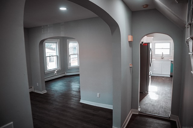 corridor featuring baseboard heating, lofted ceiling, and dark hardwood / wood-style floors