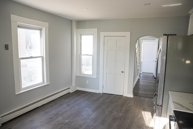 kitchen featuring dark wood-type flooring, light stone counters, a wealth of natural light, and a baseboard heating unit