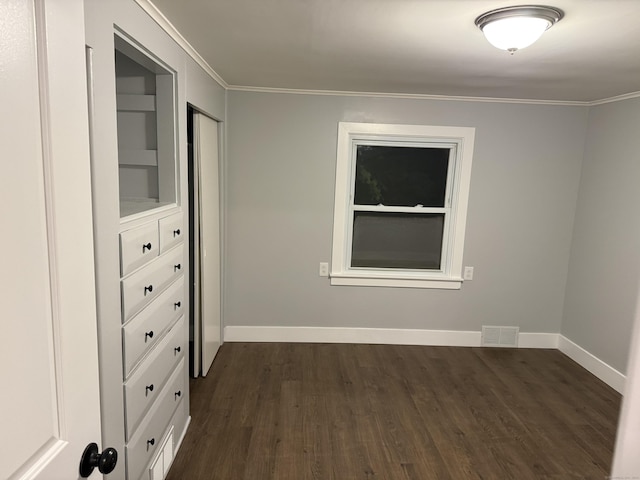 spare room with built in shelves, crown molding, and dark hardwood / wood-style floors