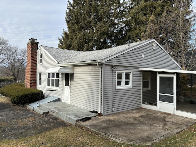 view of side of property featuring a sunroom and a patio area