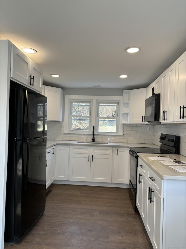 kitchen with sink, white cabinetry, black appliances, and dark hardwood / wood-style flooring