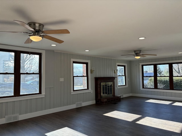 unfurnished living room with a fireplace, a healthy amount of sunlight, and dark hardwood / wood-style flooring