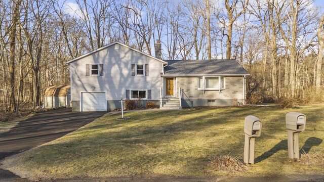 split level home featuring aphalt driveway, a chimney, an attached garage, and a front yard