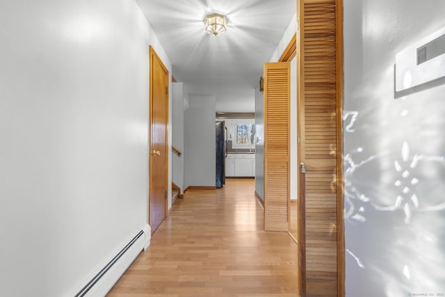 corridor with baseboards, light wood-style flooring, and baseboard heating